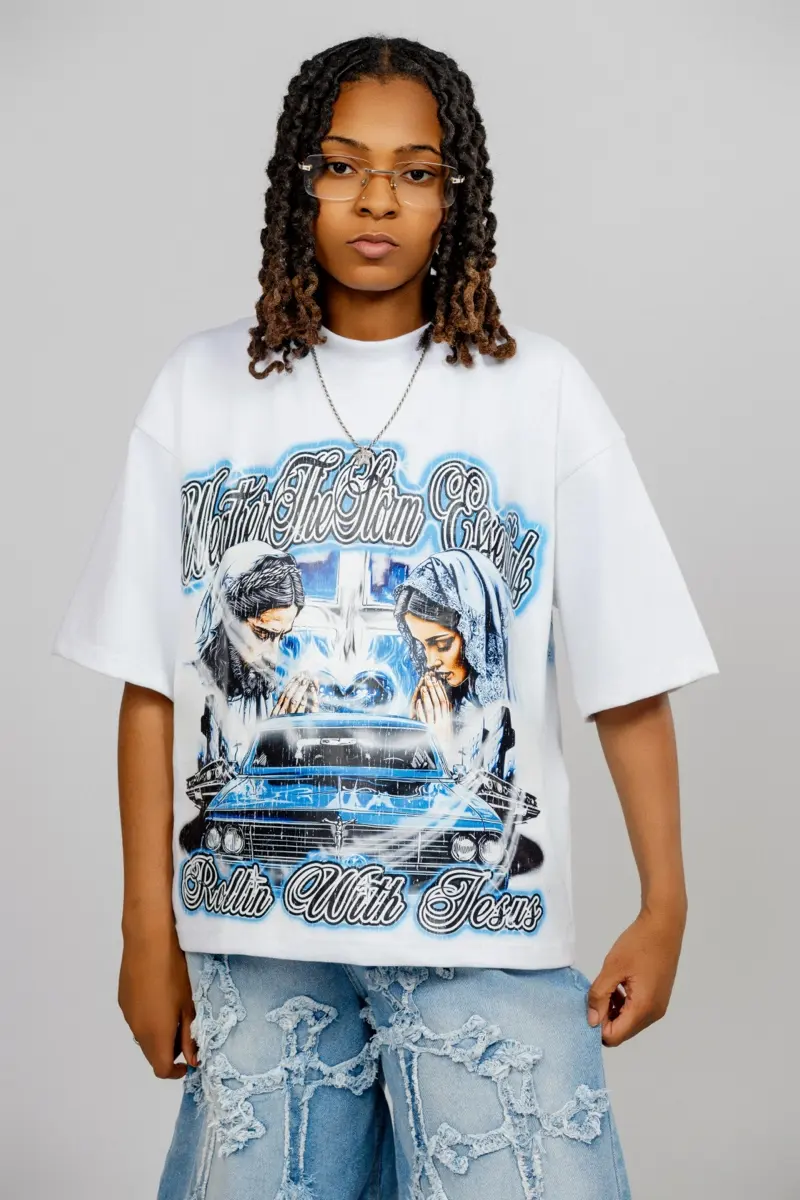 A model in an oversized WeatherTheStorm graphic tee and distressed denim shorts against a pale backdrop