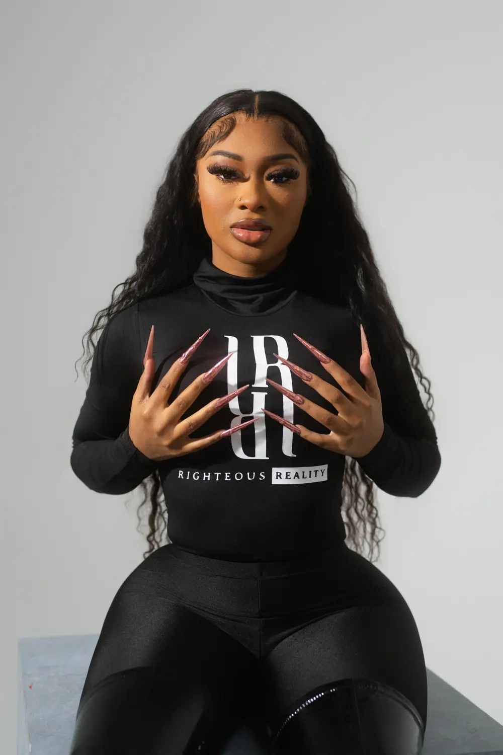 A model in a black Righteous Reality long sleeve, her long nails framing the logo