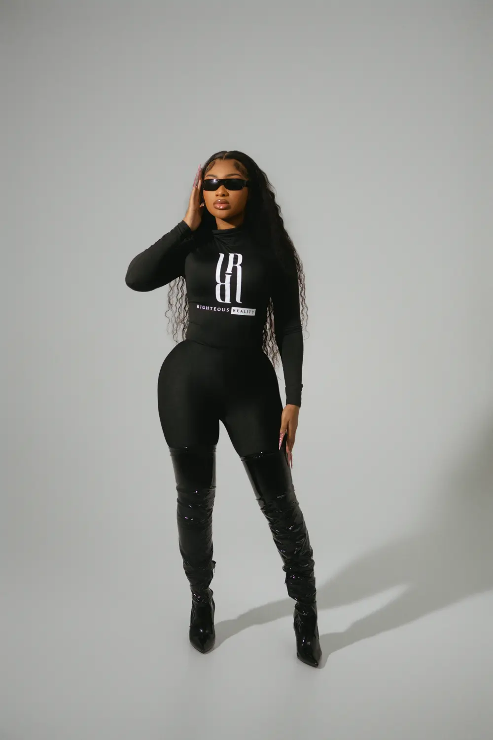 A model in a black Righteous Reality long sleeve and leggings, standing full length in sunglasses